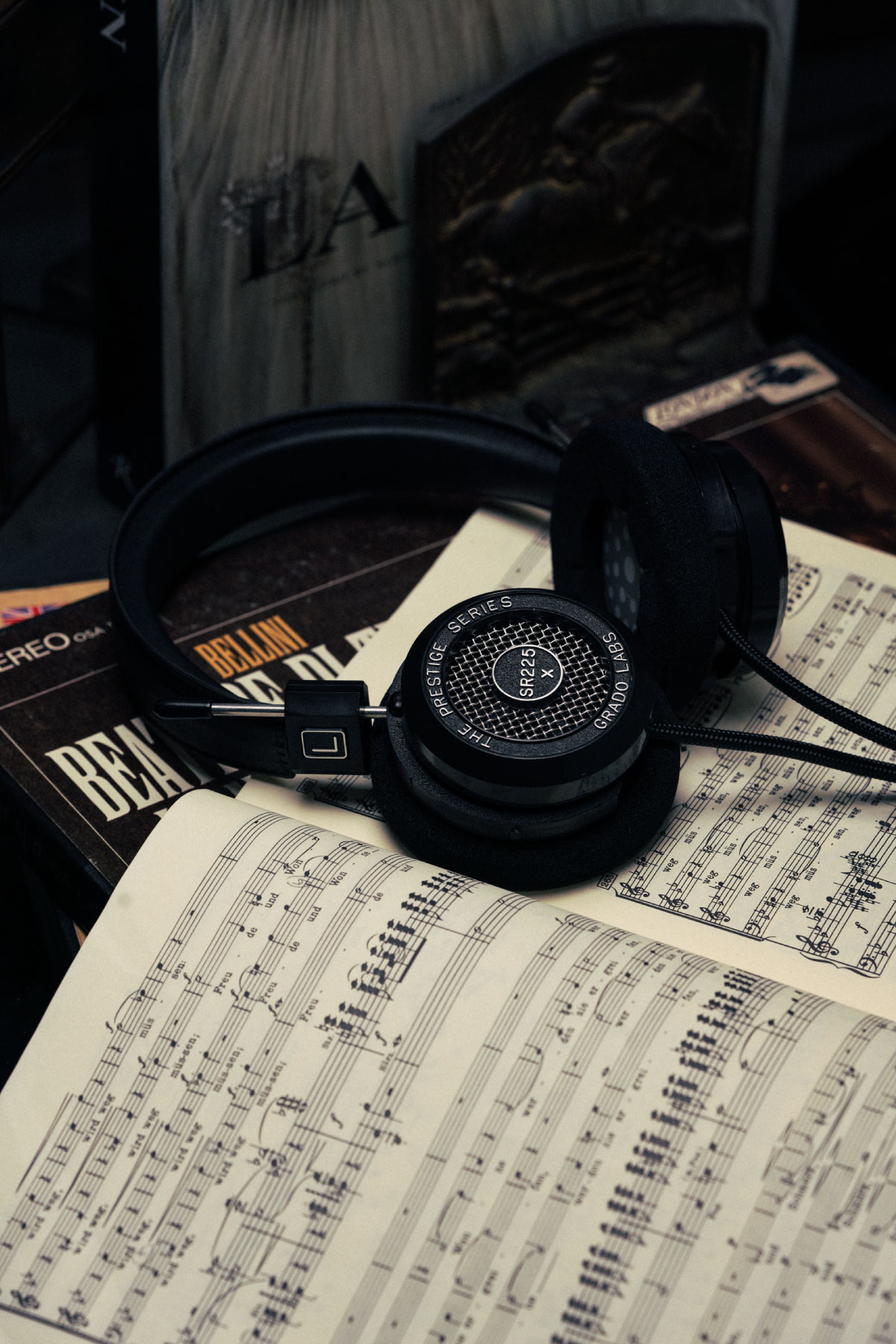 Photo of sr225x headphones resting on top of an open book with musical notation.